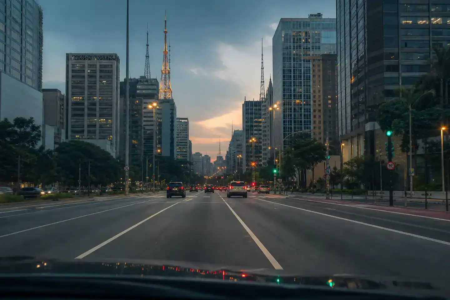 A broad city avenue between high-rise buildings at dusk